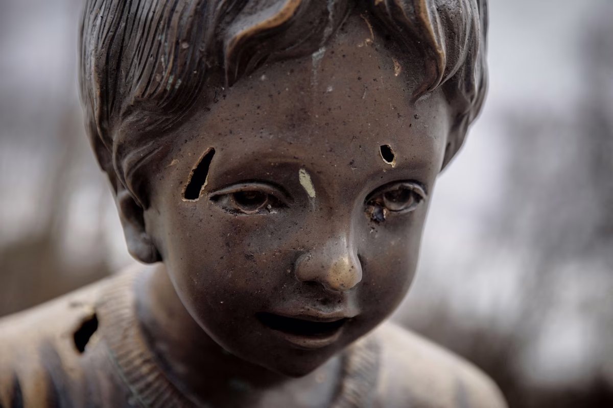 Shrapnel marks are seen on the statue of a child after shelling hit Gorky Park, an amusement park in Kharkiv, on April 2, 2022.